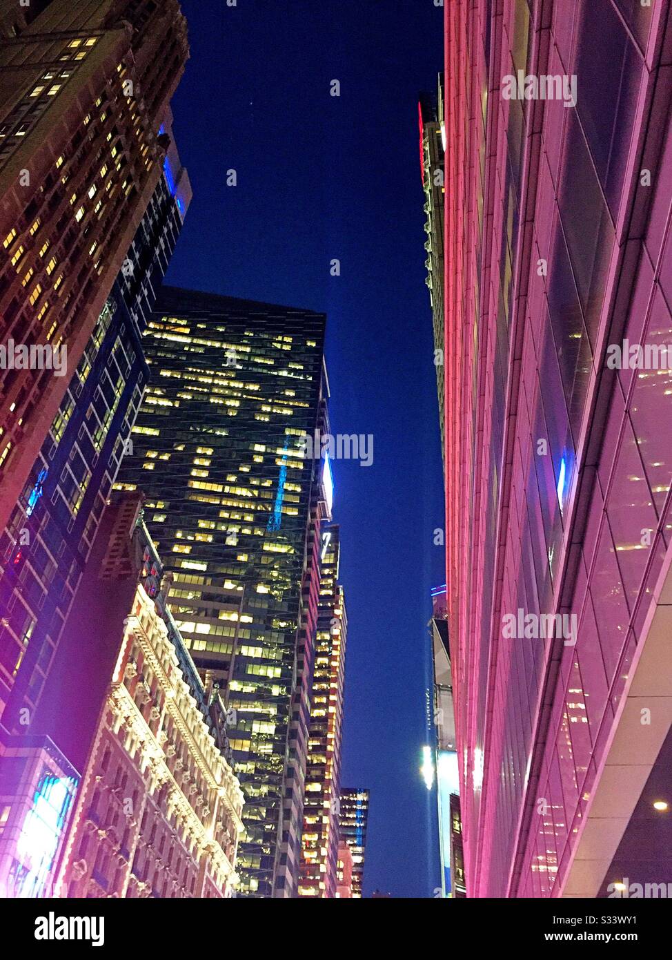 Helle Lichter und Bürogebäude nachts in der Nähe des Times Square in Midtown Manhattan, New York City, Vereinigte Staaten - Smartphone-aufgenommenes Stockfoto