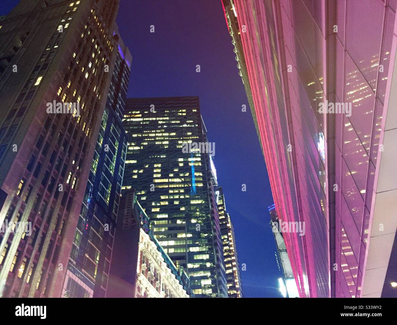Helles Licht- und Bürogebäude in der Nacht auf der 42. St. in New York City, USA - Smartphone-aufgenommenes Stockfoto