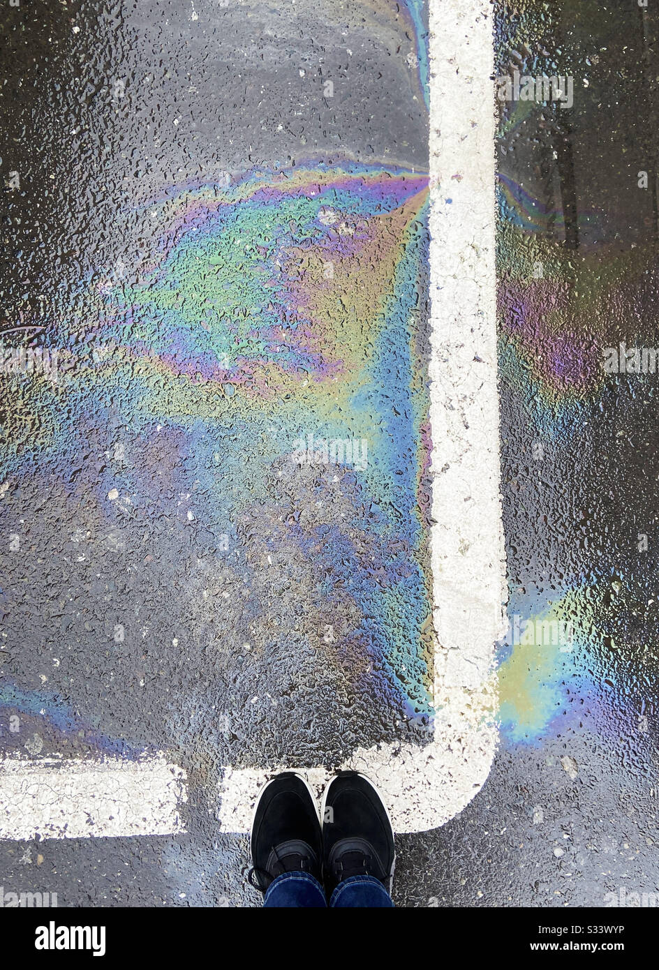 Blick auf Turnschuhe und Ölpest auf die Straßenmarkierung Stockfoto