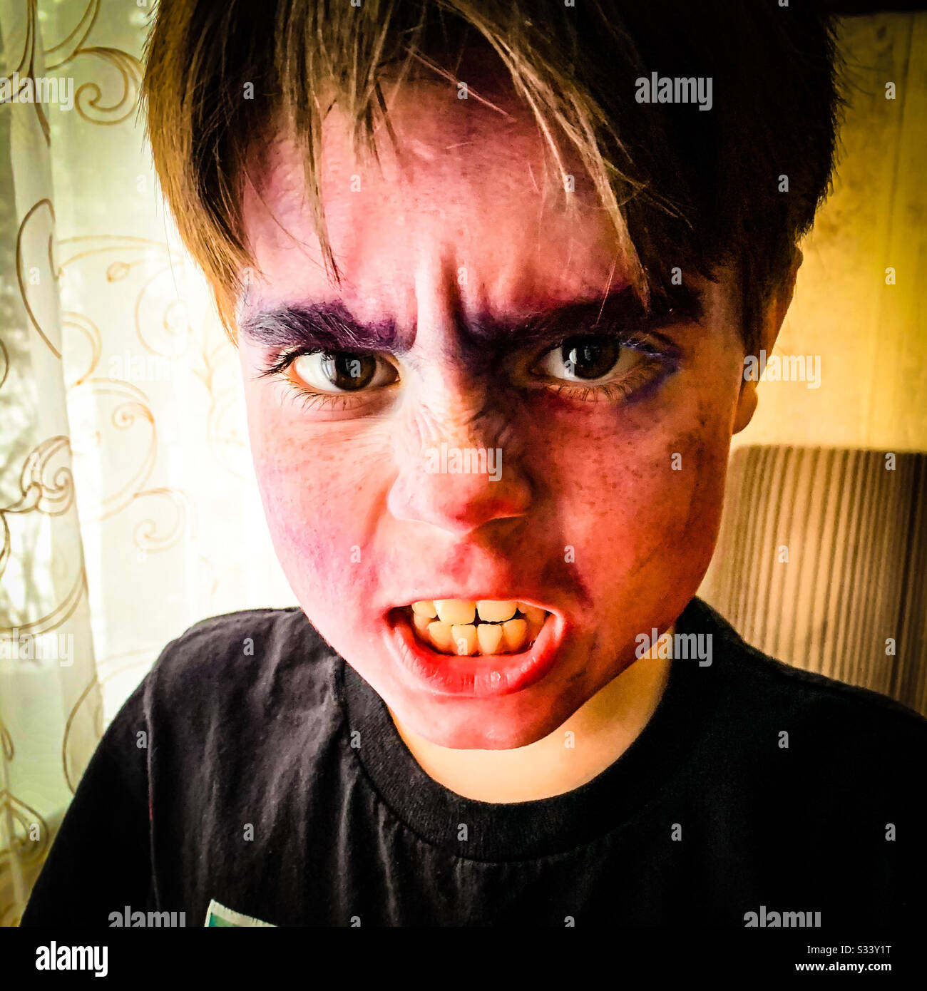 Ein zehnjähriger Junge mit Film-Make-up auf Snarls an der Kamera. Stockfoto