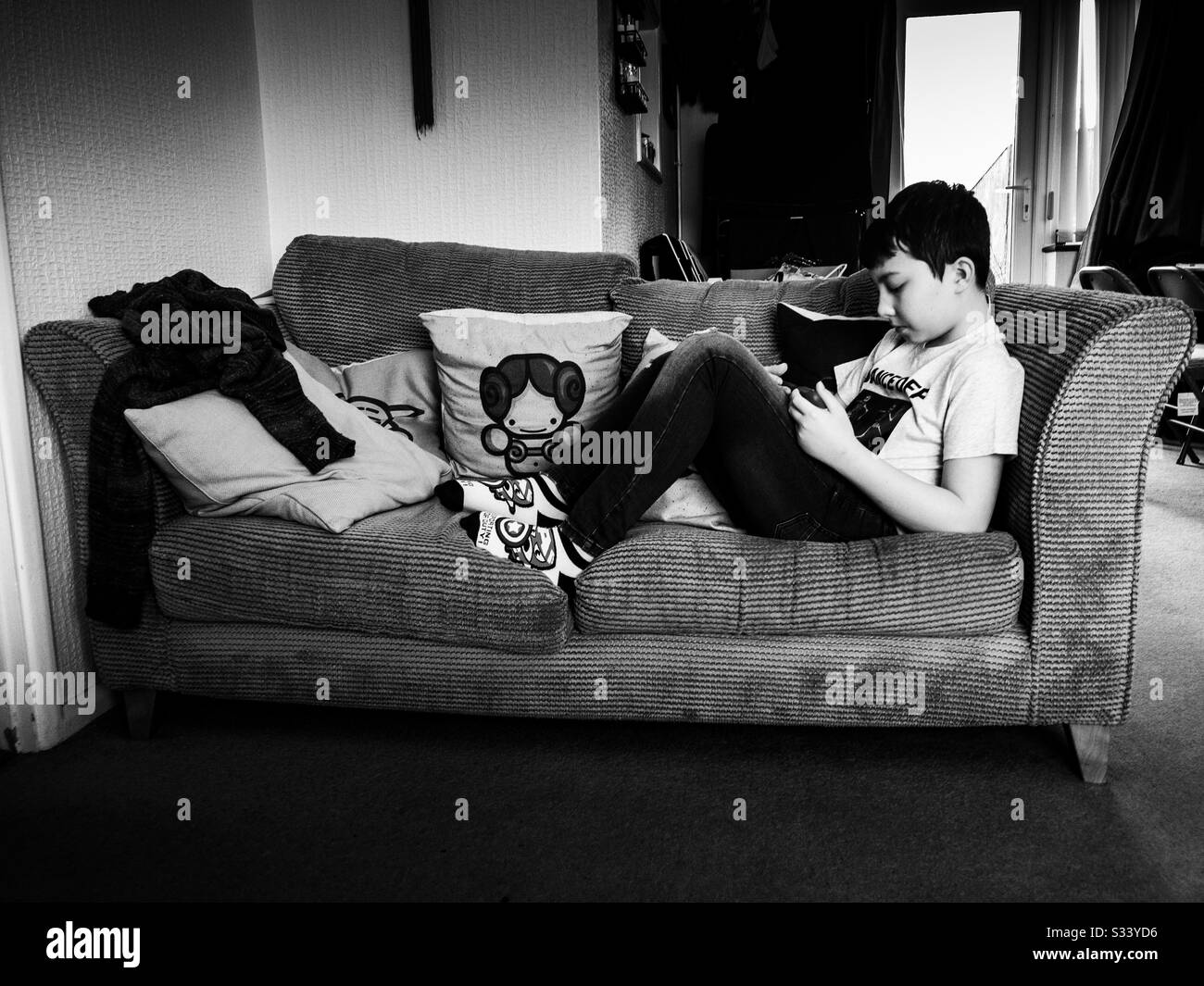 Ein Junge saß mit einem Tablet-pc auf einem Sofa. Stockfoto