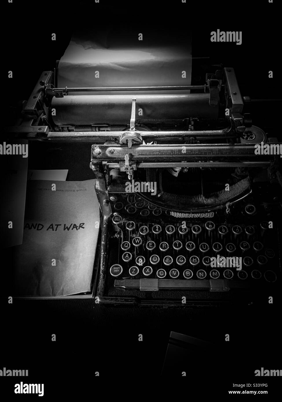 Alte Schreibmaschine auf einem Schreibtisch mit Buch "England im Krieg" zur Seite. Fotografiert im Tatton Park, Cheshire. Kriegsraum, Kriegszeit, 2. Weltkrieg Stockfoto