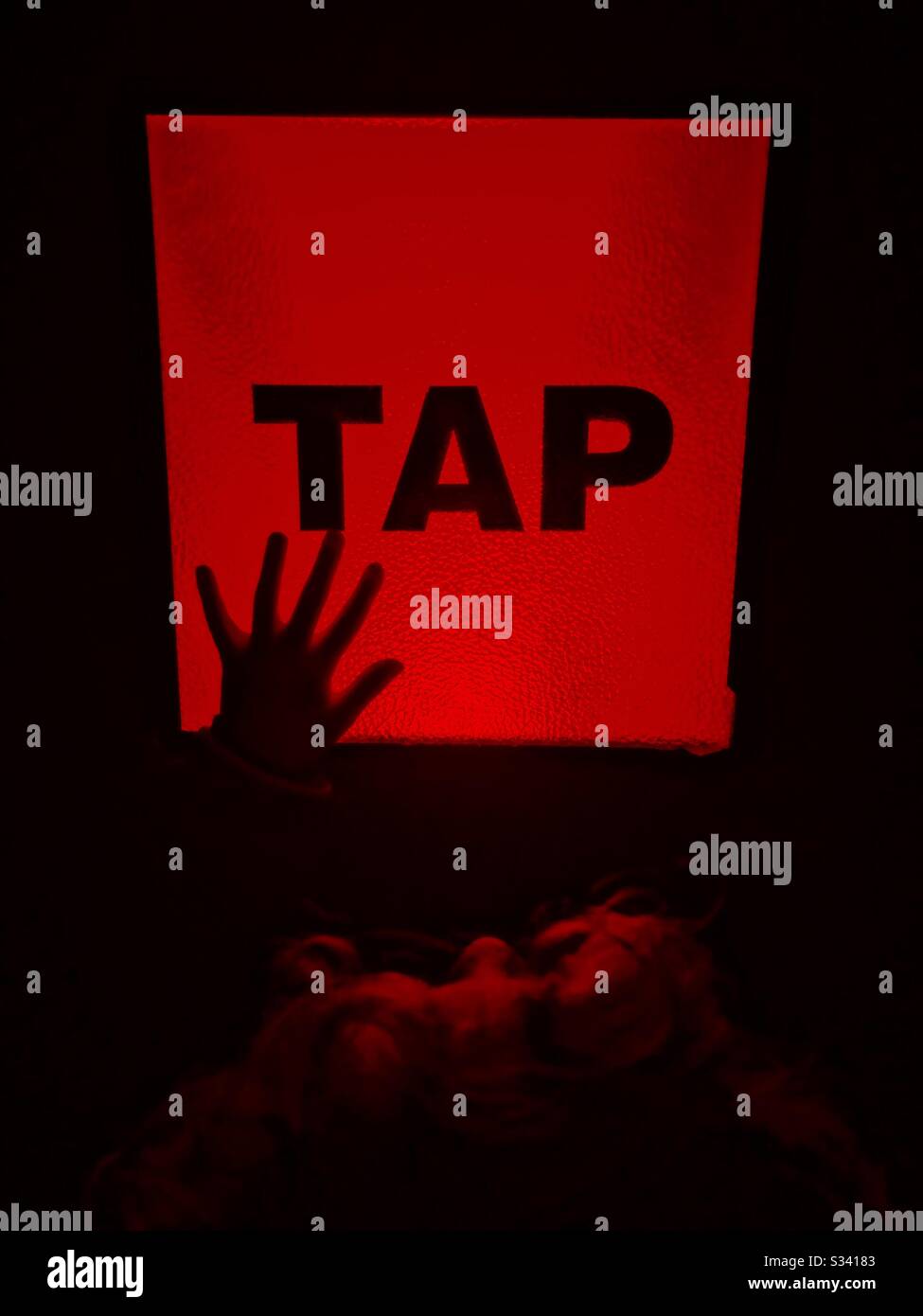 Rot leuchtende Taste mit dem Wort "Tippen" und der Silhouette der Hand des Kindes. Stockfoto