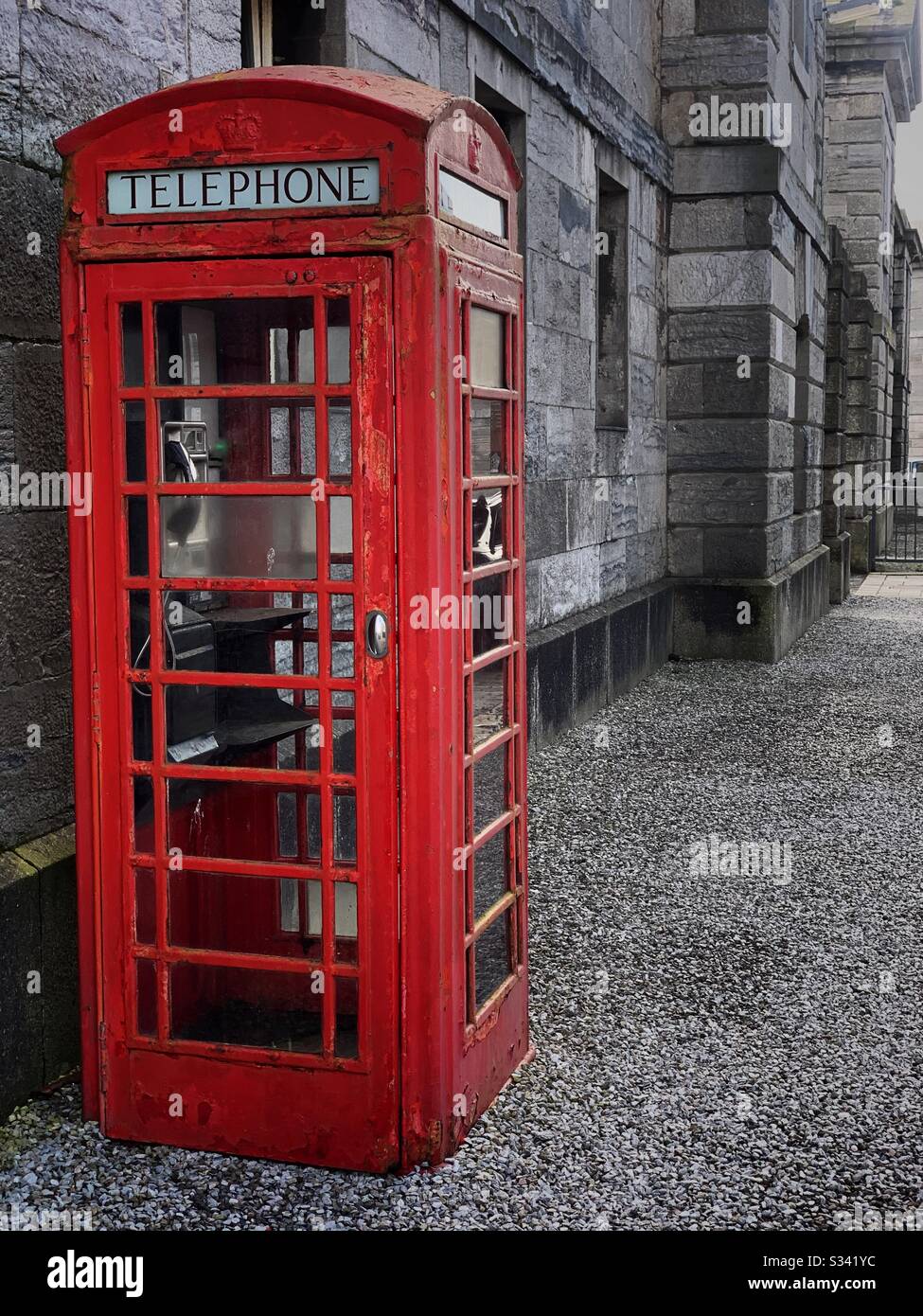 Britische rote Telefonbox gegen Steinwände Stockfoto