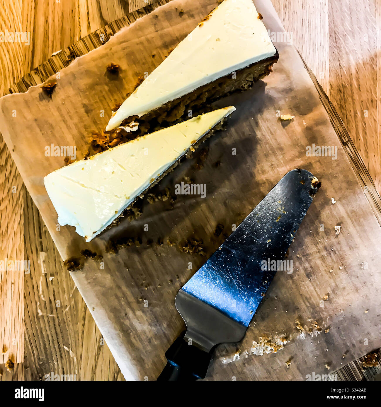 Zwei Scheiben Kuchen und ein Spachtel auf einem Holzservierbrett Stockfoto