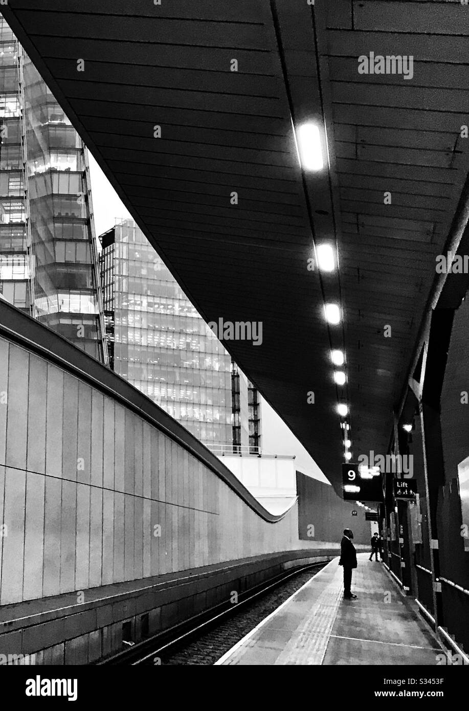 Silhouette des Mannes, der auf dem Bahnsteig mit Wolkenkratzern im Hintergrund steht Stockfoto