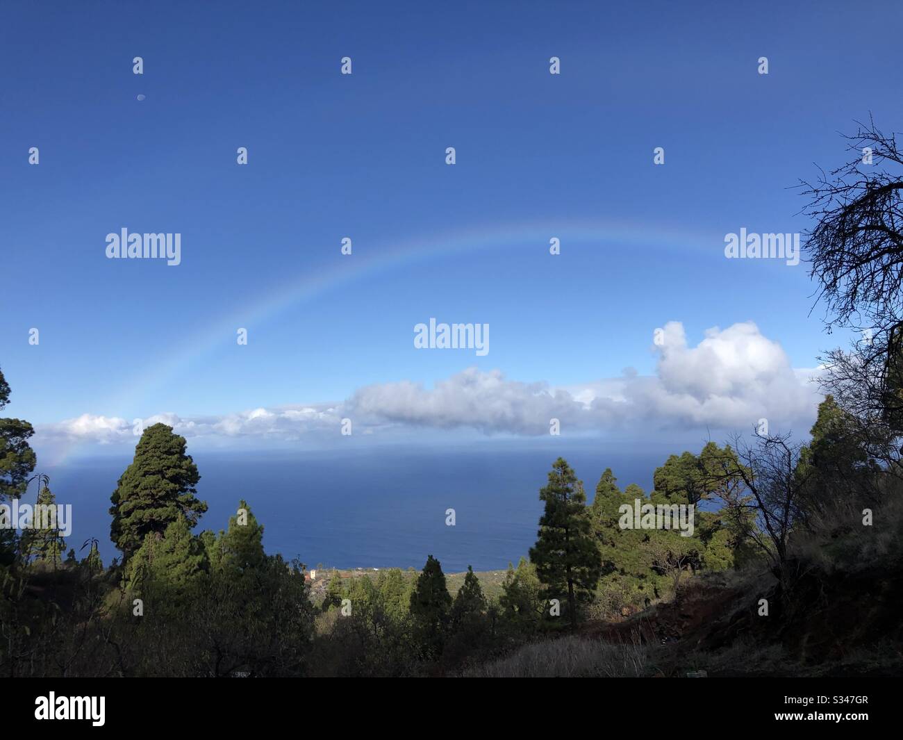 Ein Regenbogen mit wunderschönen cumulus-wolken und der Mond oben links. Ein klarer Tag aufs Meer. Stockfoto