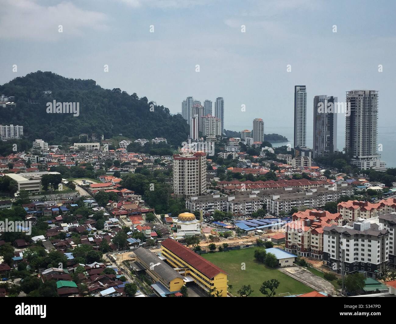 Alt und neu: Das ursprüngliche Dorf Kampung Belachan, mit neueren Wohnblöcken und Häusern jenseits, George Town, Penang, Malaysia - Smartphone-aufgenommenes Stockfoto