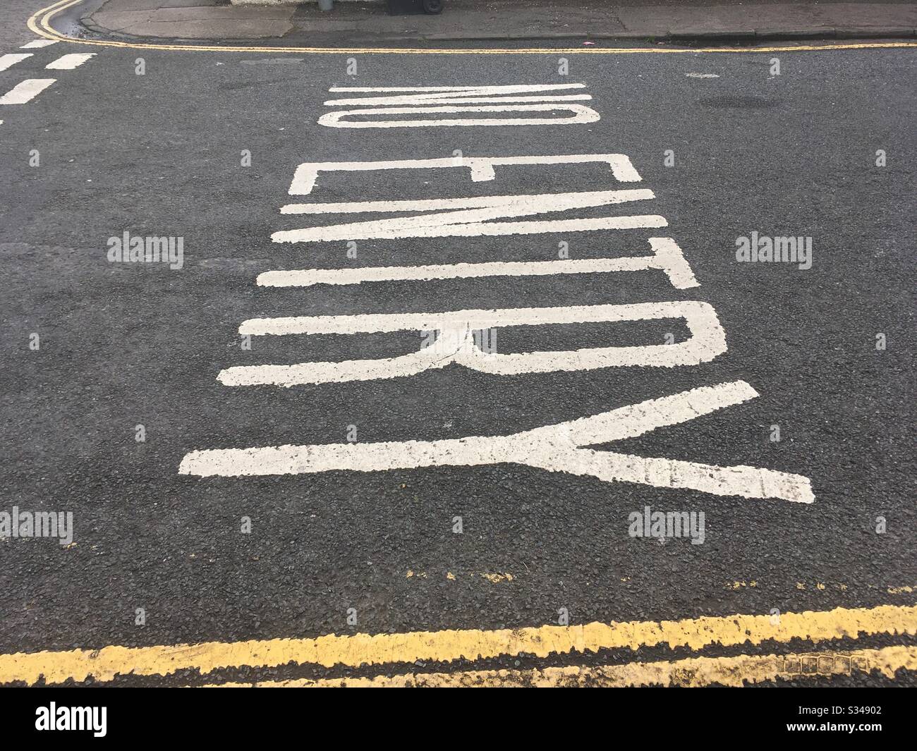 Keine Straßenmarkierungen in weißer Farbe auf einer Straßenoberfläche an einer Kreuzung in Großbritannien Stockfoto