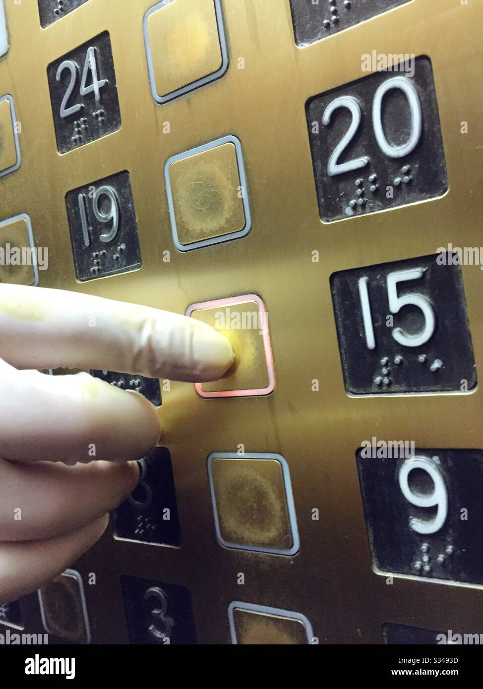 Covid-19 Vorsorge, die von einer Person praktiziert wird, die Latexhandschuhe trägt, wenn sie während der globalen Pandemie des Coronavirus einen Aufzugknopf drückt, um eine Ausbreitung der Keime, USA, zu verhindern - Smartphone-aufgenommenes Stockfoto