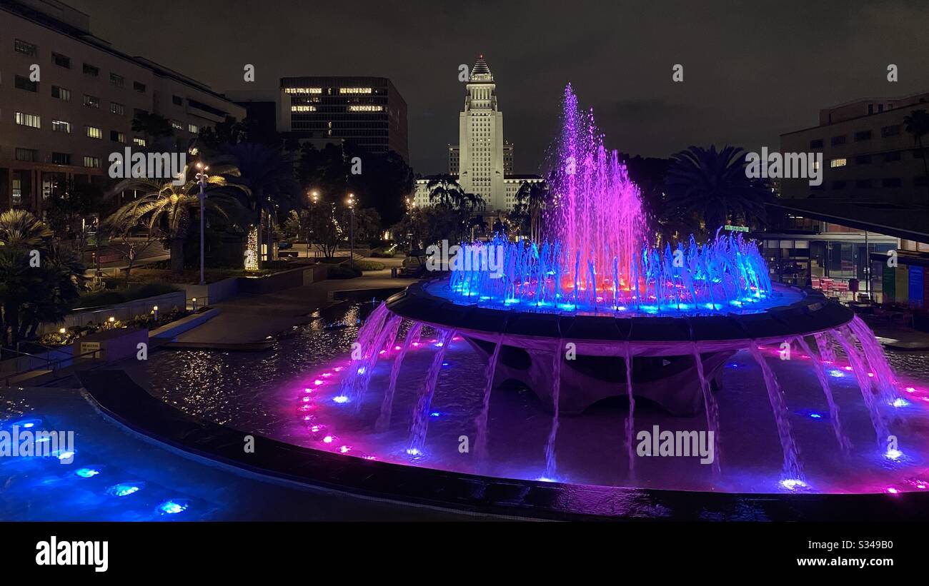 LOS ANGELES, CA, MAR 2020: Springbrunnen im Grand Park, Civic Center, Downtown in der Nacht. Leuchtet mit rosafarbenen und blauen Lichtern. Rathaus im Hintergrund Stockfoto