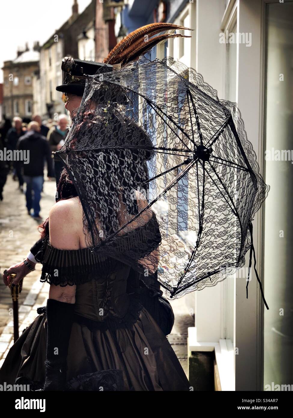 Menschen in kreativen Kostümen während einer Cosplay-Veranstaltung. Whitby Goth Weekend. Frau hält schwarzen Spitzen-Gothic-Regenschirm Stockfoto