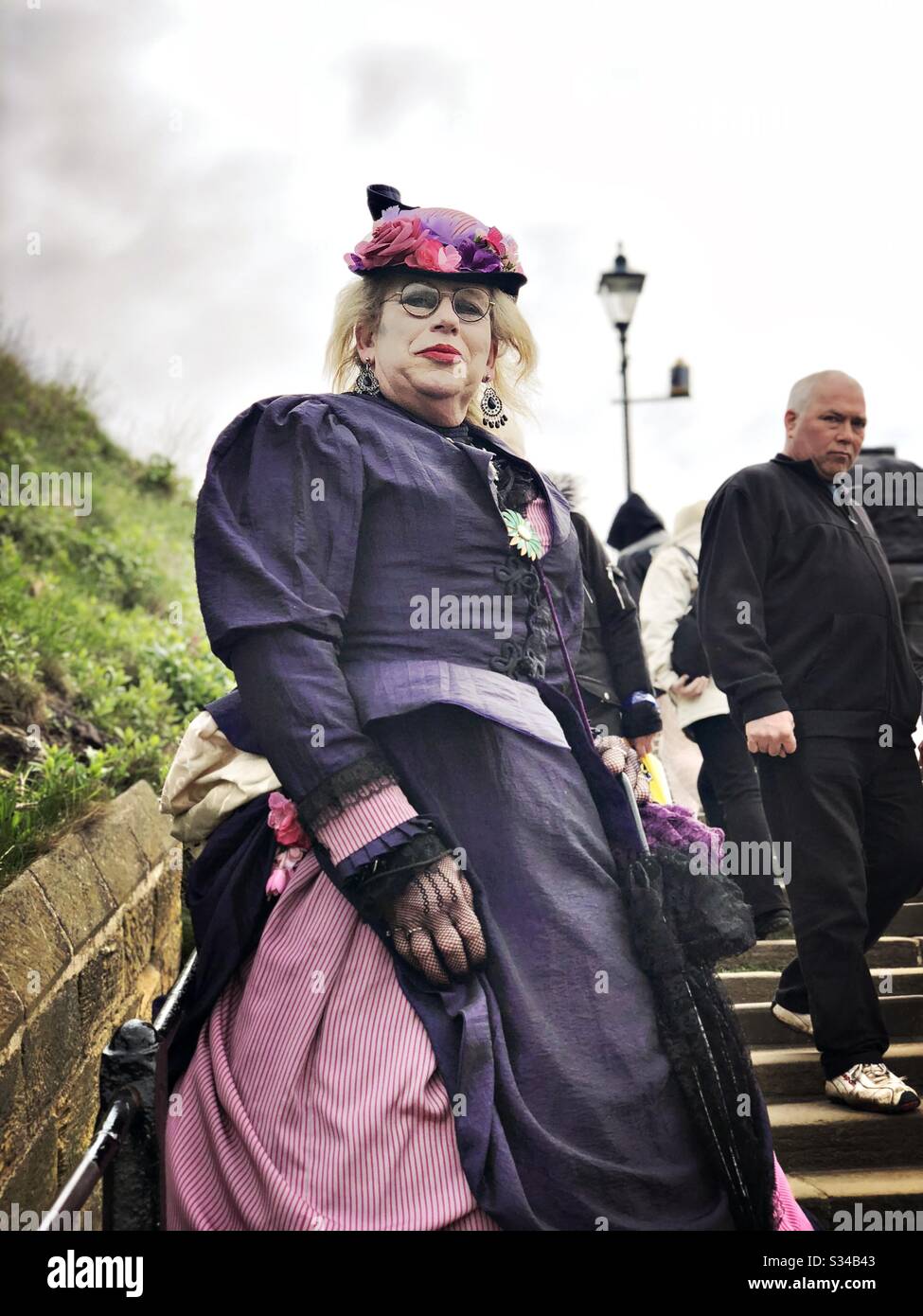 Person in einem kreativen Kostüm während einer Cosplay-Veranstaltung. Whitby Goth Weekend. Ältere Frau im Vintage-Goth-Outfit - Smartphone-aufgenommenes Stockfoto