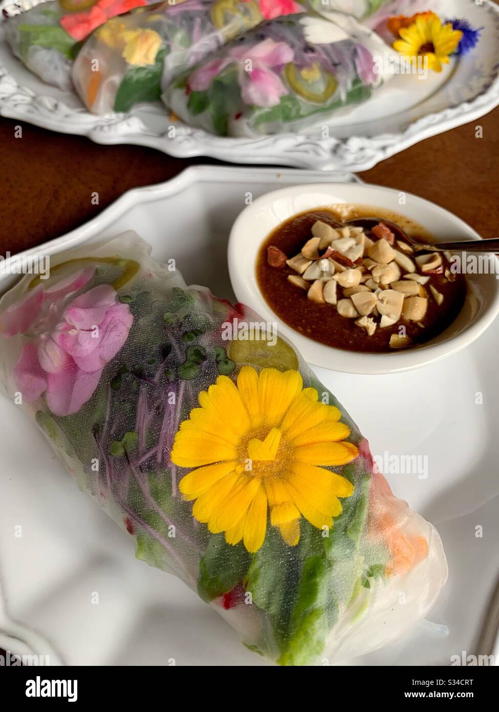 Hausgemachte Frühlingsrollen mit frischem Gemüse und essbaren Blumen. Stockfoto