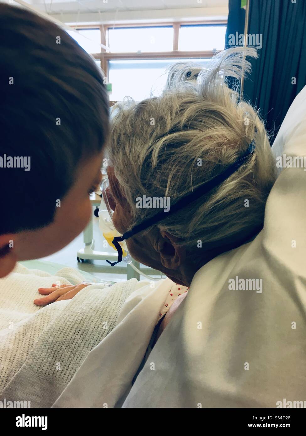 Junge, der ältere Verwandte im Krankenhaus küsst - Smartphone-aufgenommenes Stockfoto