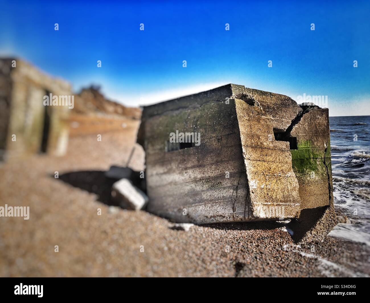 Kriegsschutz am Strand aufgrund der Auswirkungen der Küstenerosion, Bawdsey, Suffolk, England. - Smartphone-aufgenommenes Stockfoto