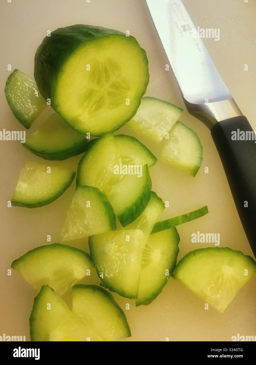 Eine englische Gurke, die mit einem Messer auf einem Schneidebrett geschnitten wurde Stockfoto