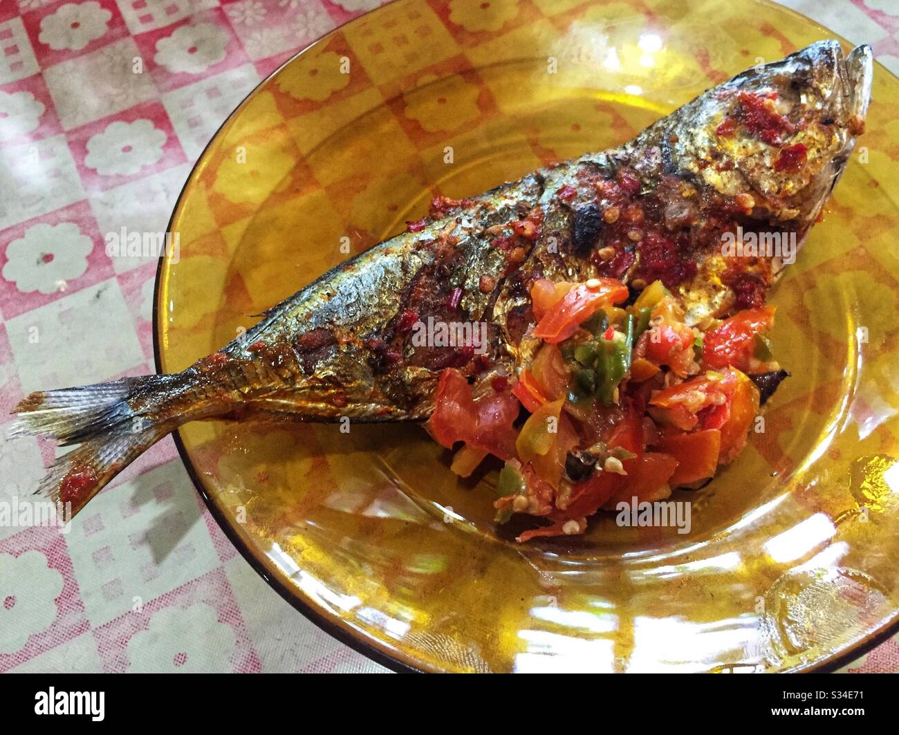 Ein gegrillter Fisch mit Dabu-dabu Sambal auf der Glasplatte. Stockfoto
