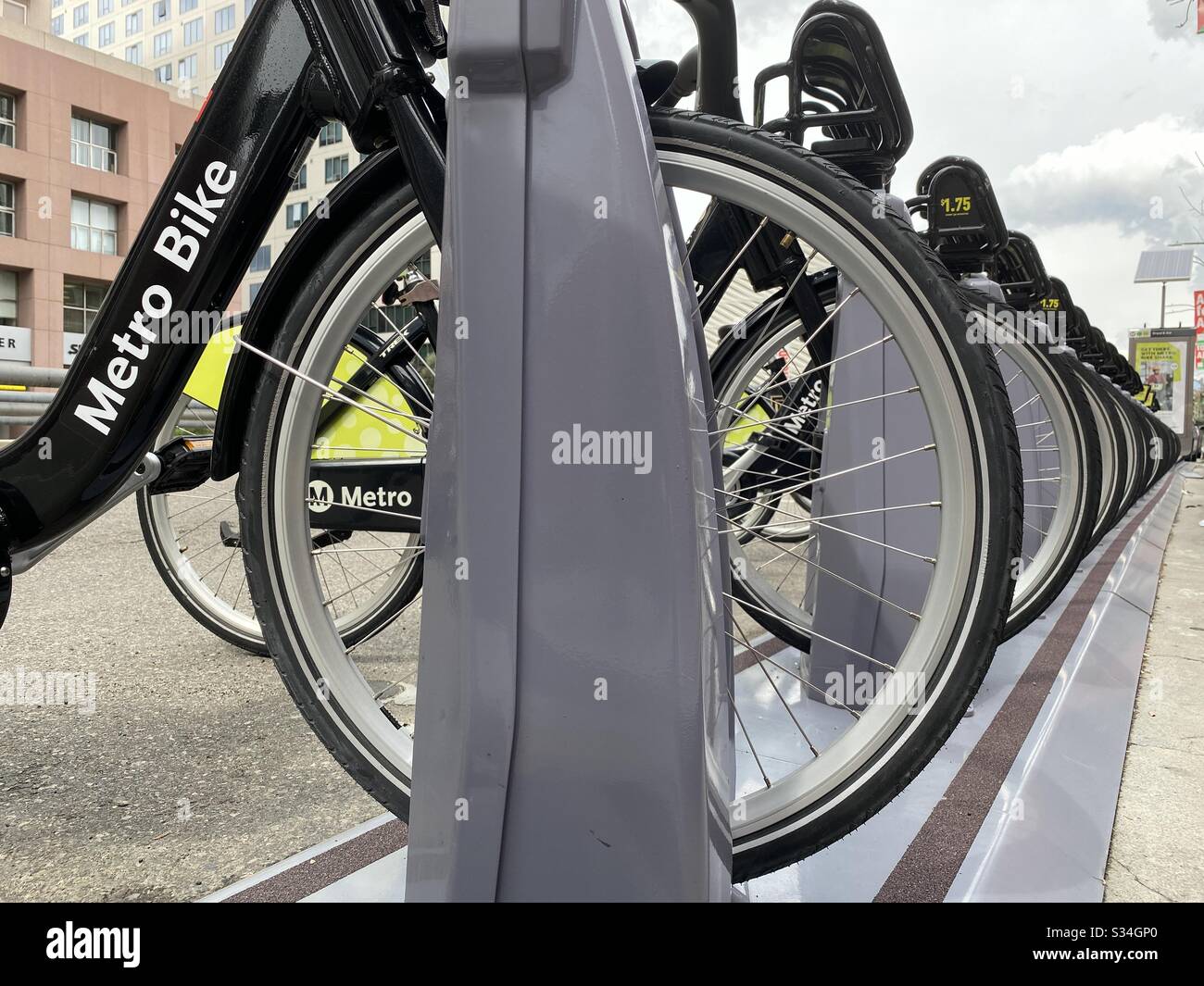 LOS ANGELES, CA, MAR 2020: Radhoher Blick auf das schwarze und grüne LA Metro Bike Share Leihfahrräder im Dock in der Nähe von Museen in der Innenstadt. Betonung auf Logo Stockfoto