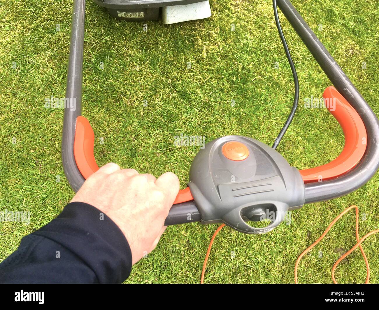 Manns Hand am Rasenmähergriff - Smartphone-aufgenommenes Stockfoto