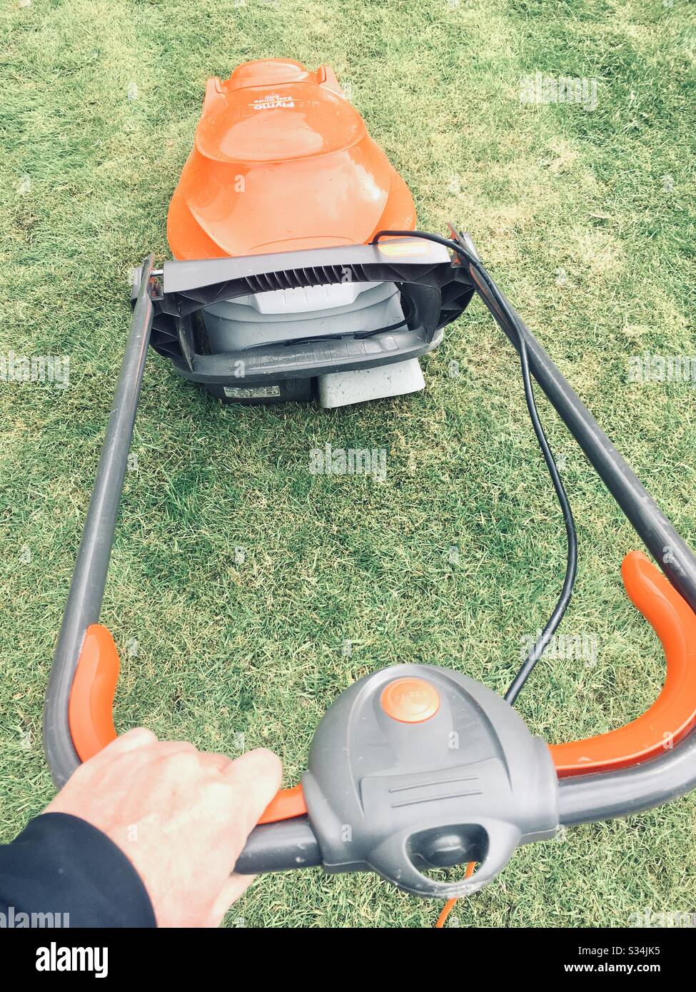 Mann mit Hand am Rasenmäher - Smartphone-aufgenommenes Stockfoto