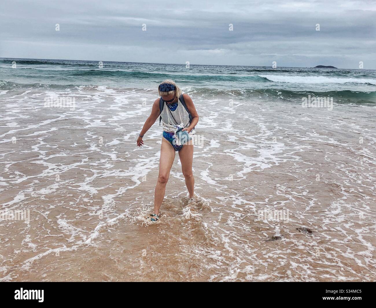 Eine Frau läuft aus dem Meer. - Smartphone-aufgenommenes Stockfoto