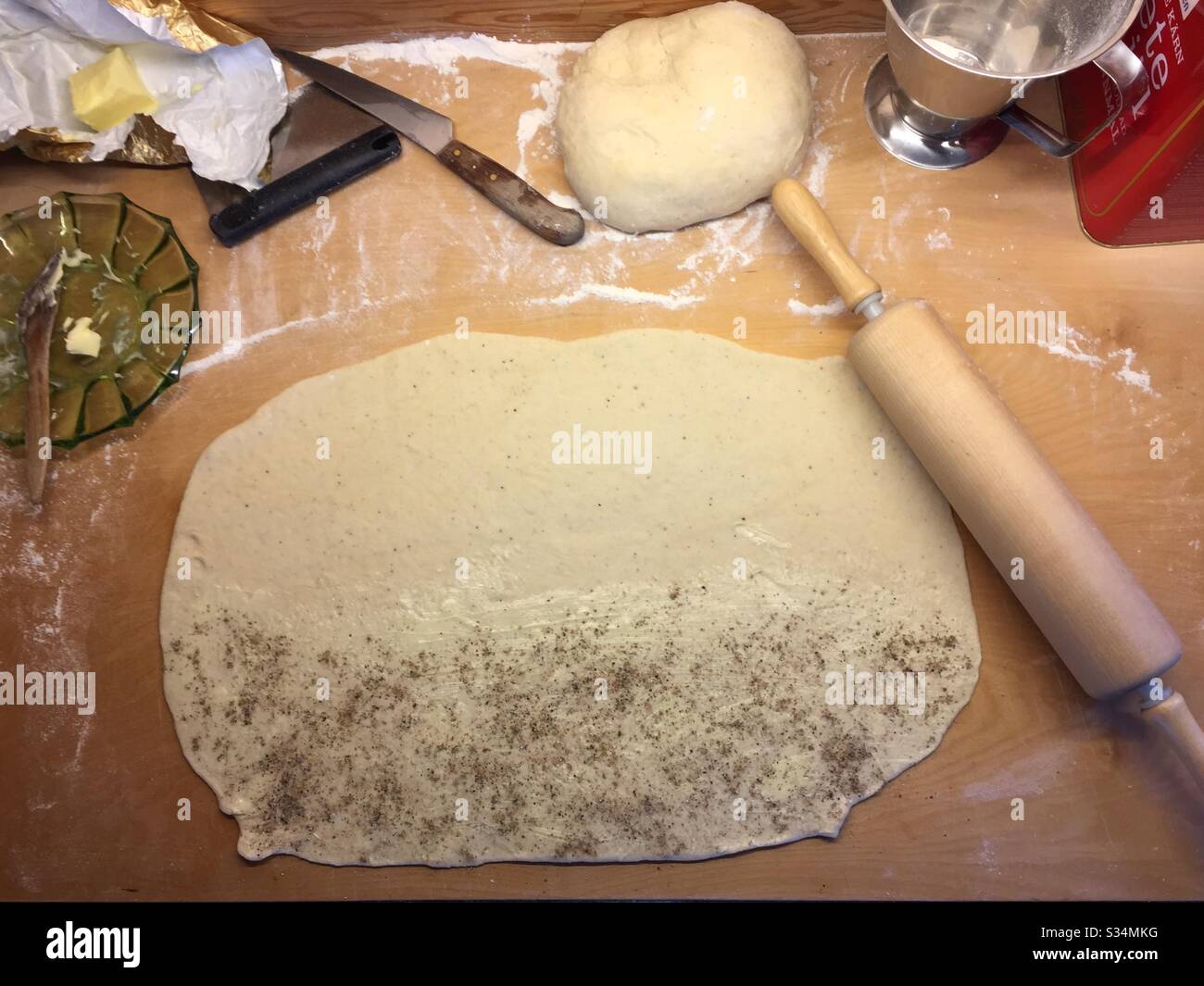 Backen von schwedischen Kardamombrötchen. Die Hälfte des Teigs ist mit gemahlenem Kardamom bedeckt. - Smartphone-aufgenommenes Stockfoto