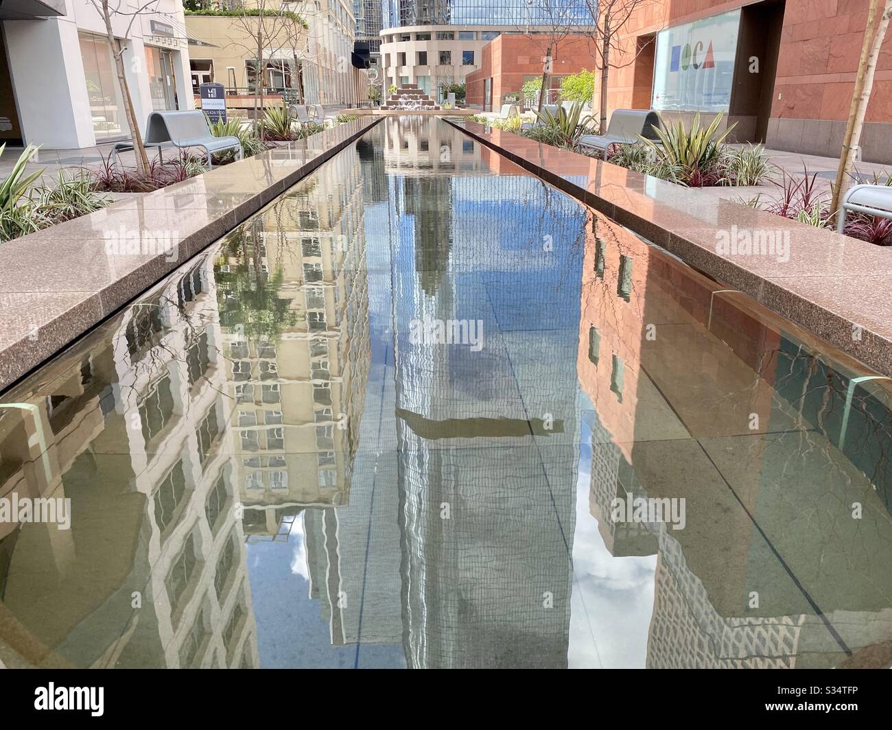 LOS ANGELES, CA, MAR 2020: Der Pool spiegelt bunte Wohnung- und Bürogebäude im Pocket Park neben dem California Plaza in der Innenstadt wider - Smartphone-aufgenommenes Stockfoto