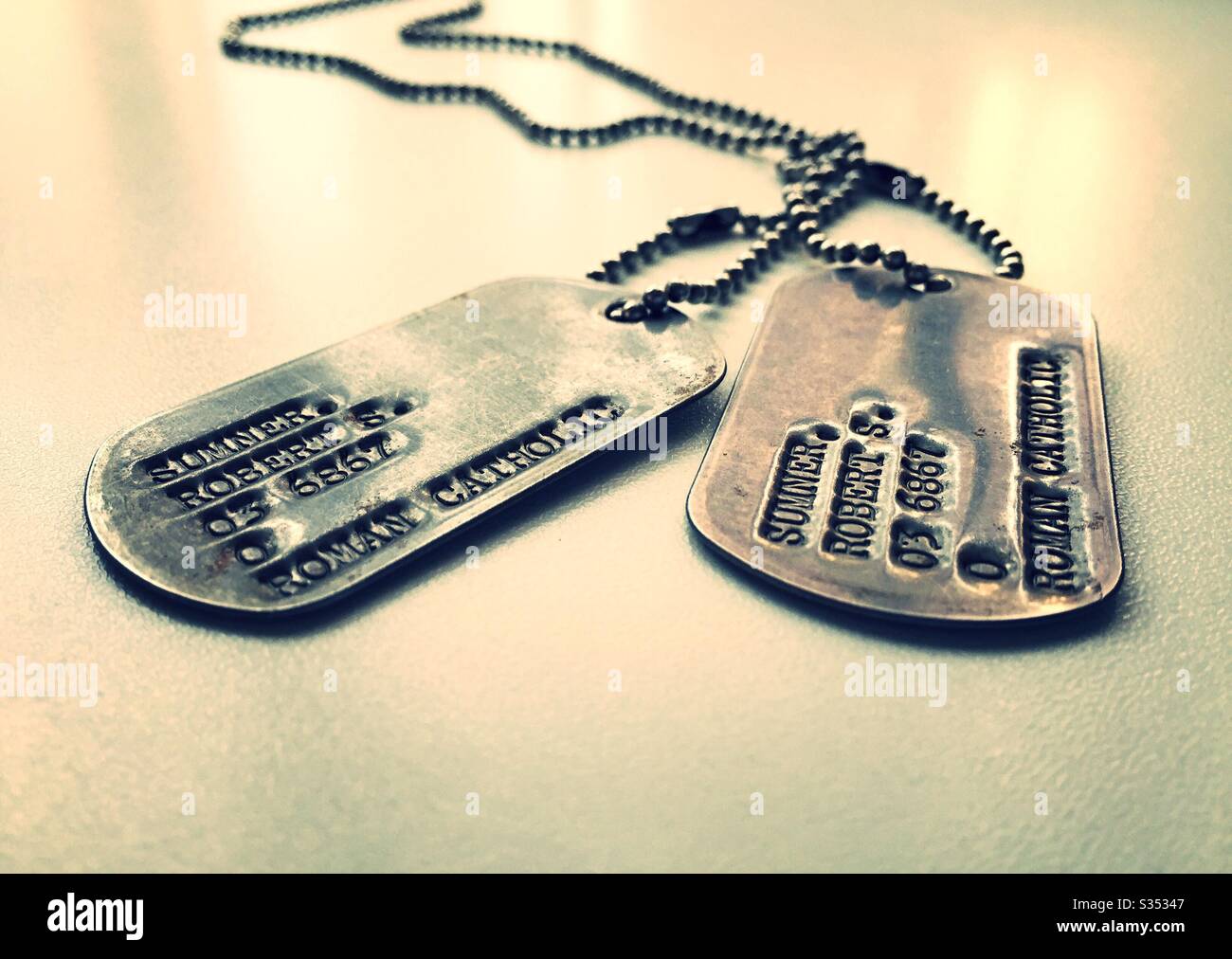 Nahaufnahme von alten Identifikationsschildern und Ketten aus der Zeit des Zweiten Weltkriegs, USA - Smartphone-aufgenommenes Stockfoto