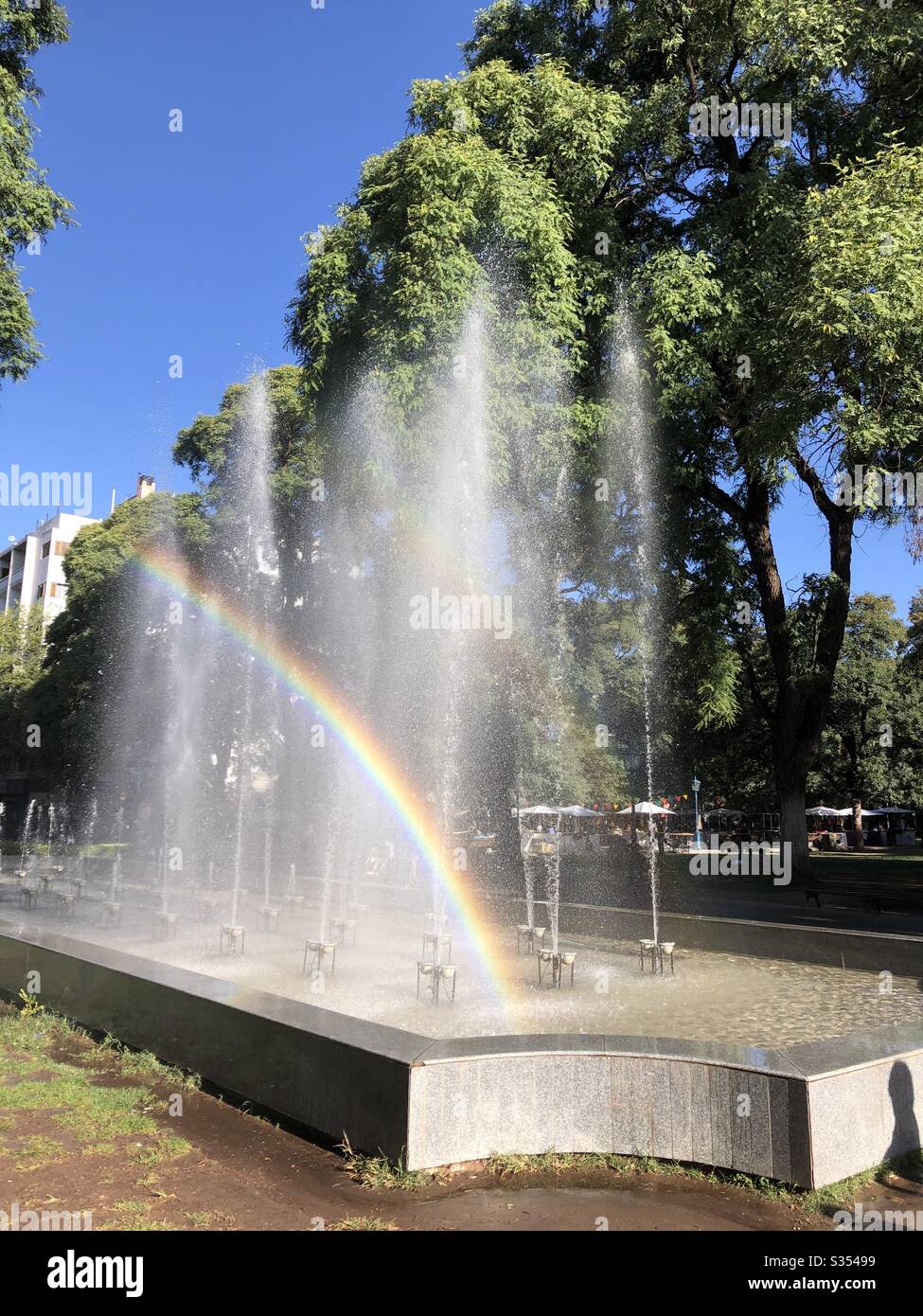 Ein Regenbogen erscheint in einem Park Wasserbrunnen in Mendoza, Argentinien. - Smartphone-aufgenommenes Stockfoto
