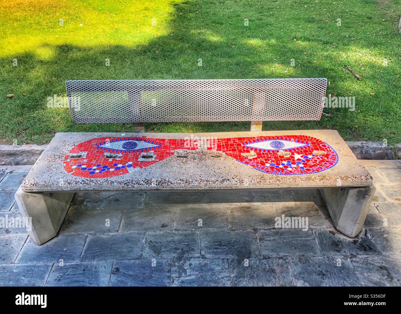 Parkbank mit rotem Mosaikmuster. - Smartphone-aufgenommenes Stockfoto