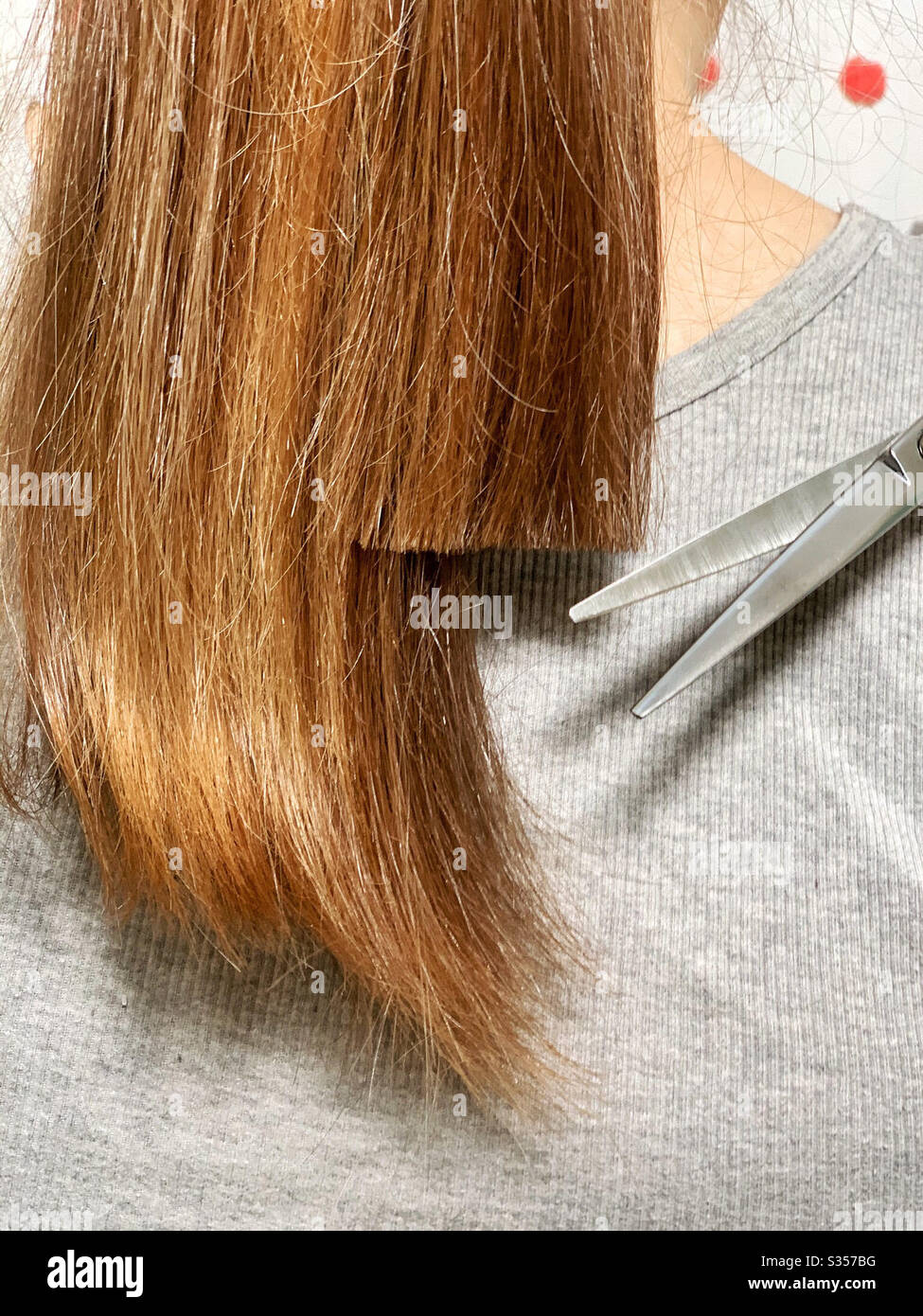 Frau schneidet sich ihre eigenen Haare zu Hause im Bad seit Salon in geschlossen - Smartphone-aufgenommenes Stockfoto