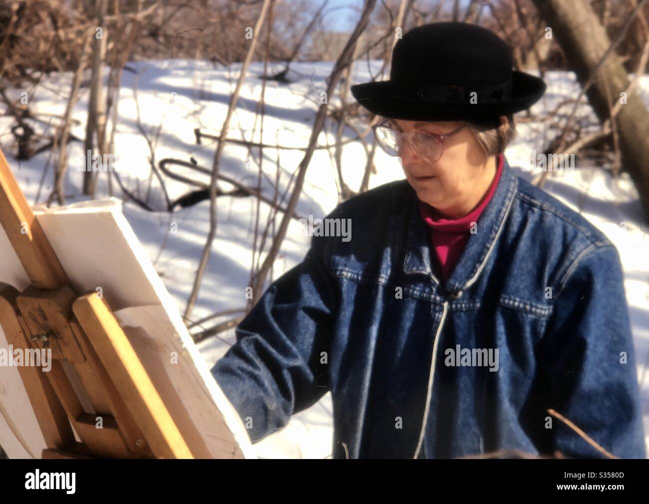 Ältere Frau Malerei Landschaft im Freien in schneebedeckten Park in Boston Bereich - Smartphone-aufgenommenes Stockfoto