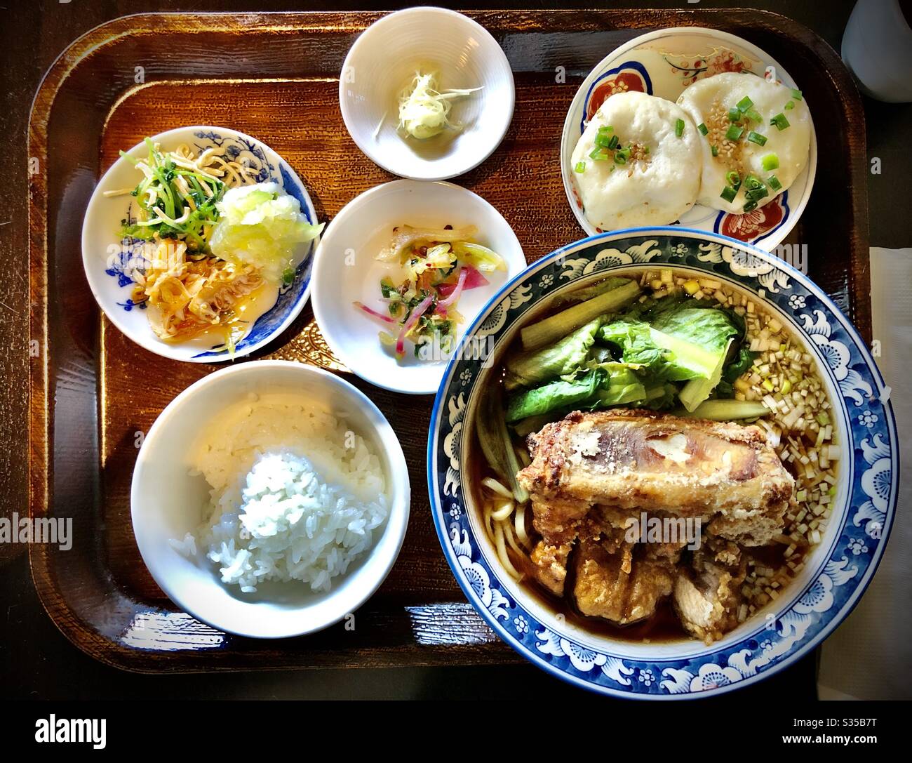 Japanisches Mittagessen mit Schweinebrippe-Nudelsuppe, Knödel, eingelegtem Gemüse und weißem Reis - Smartphone-aufgenommenes Stockfoto