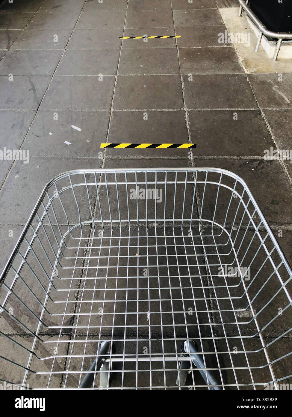 Klebeband auf dem Boden vor einem Supermarkt, um soziale Distanzierungsmaßnahmen während der Coronavirus-Pandemie umzusetzen Stockfoto