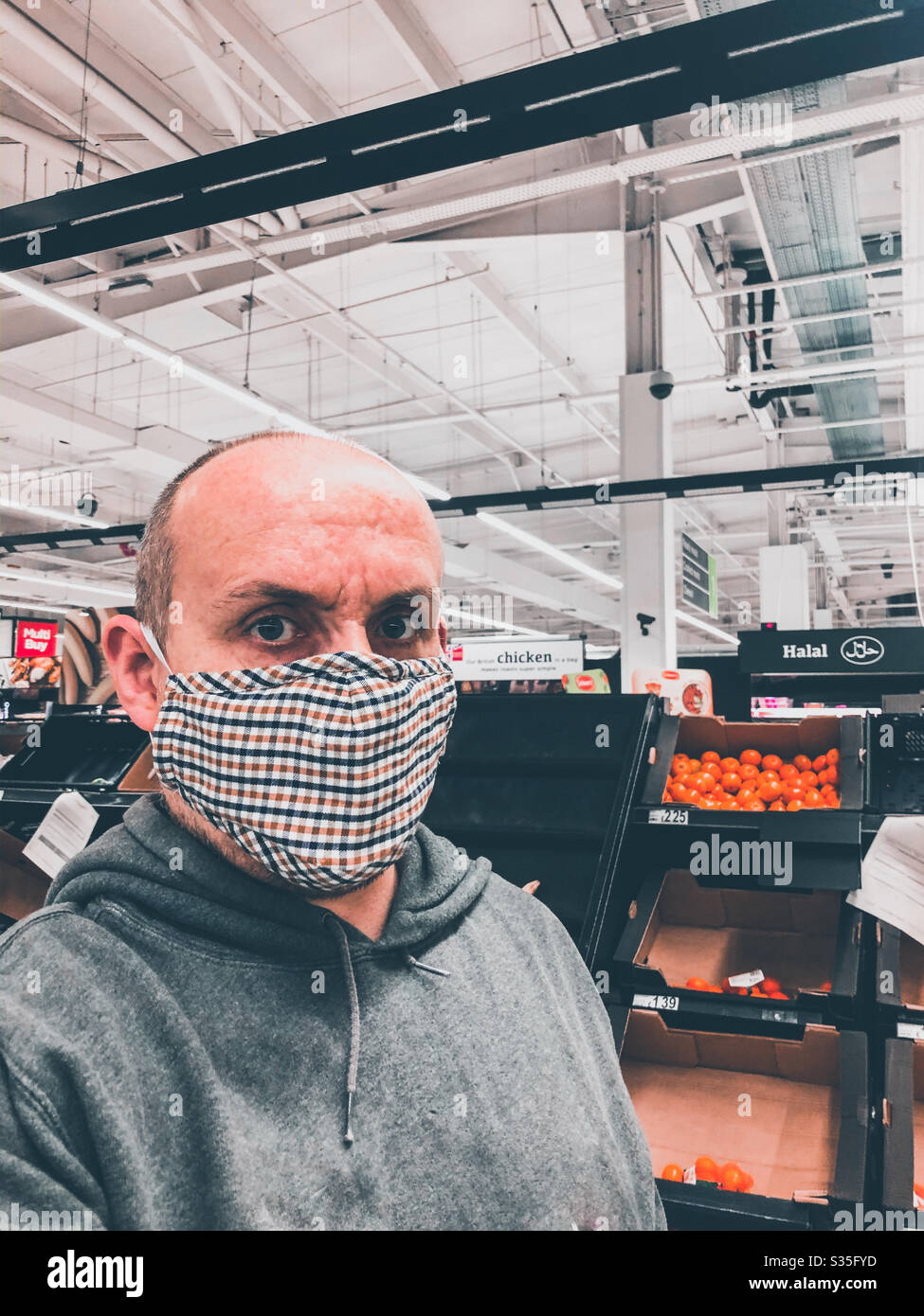 Ein Mann, der eine Gesichtsmaske trägt, während er in einem Supermarkt Lebensmittel kauft, wegen der Coronavirus-Pandemie l. Stockfoto