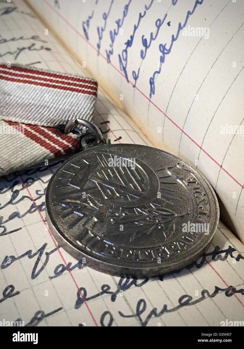 Alte russische Ehrenmedaille auf einer Seite eines handgeschriebenen Notizbuchs Stockfoto