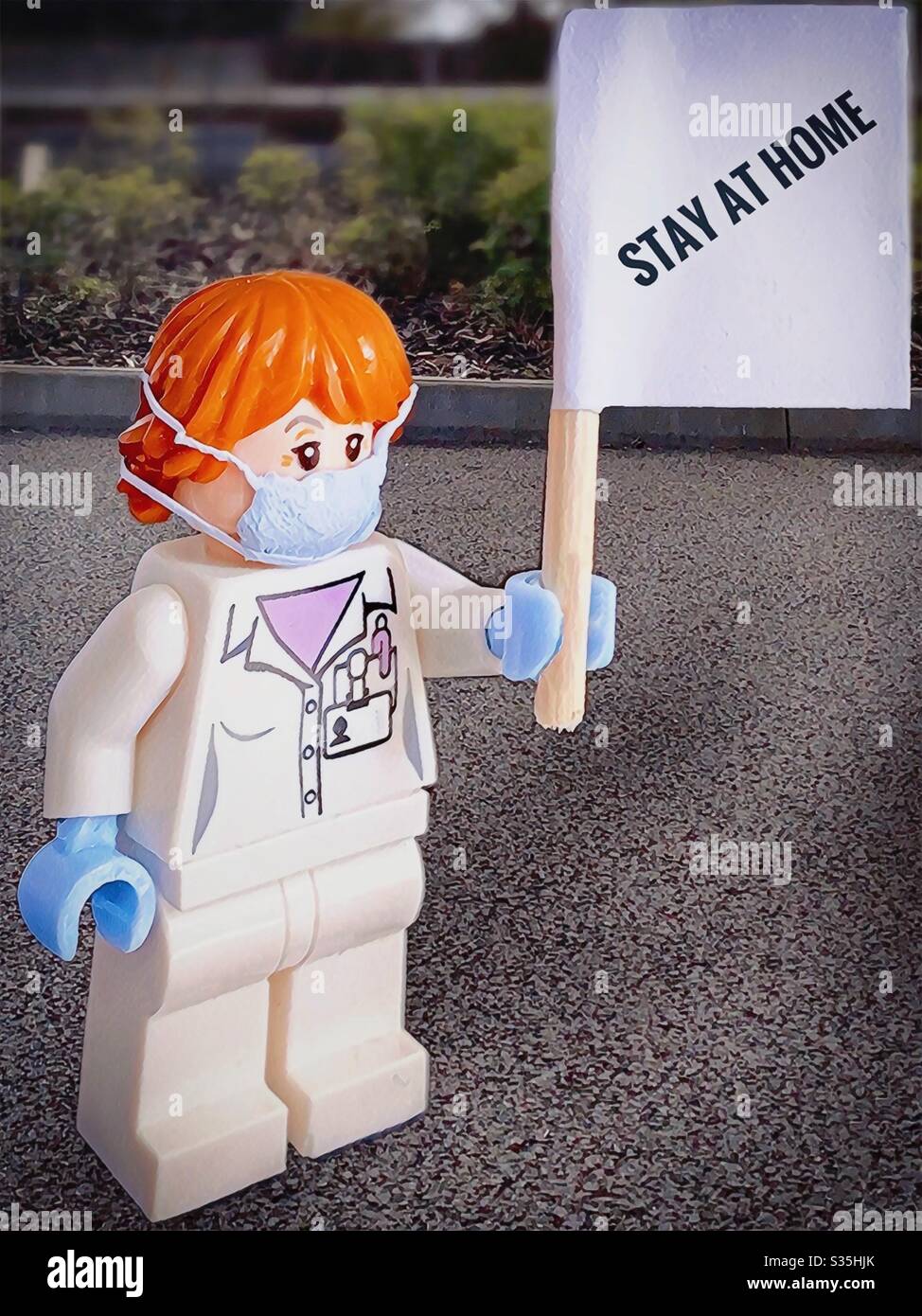 Krankenschwester oder Arzt, die während des Ausbruchs des Coronavirus-Virus ‘sCovid -19 eine medizinische Schutzmaske und Handschuhe mit Schild „zu Hause“ trägt - Smartphone-aufgenommenes Stockfoto