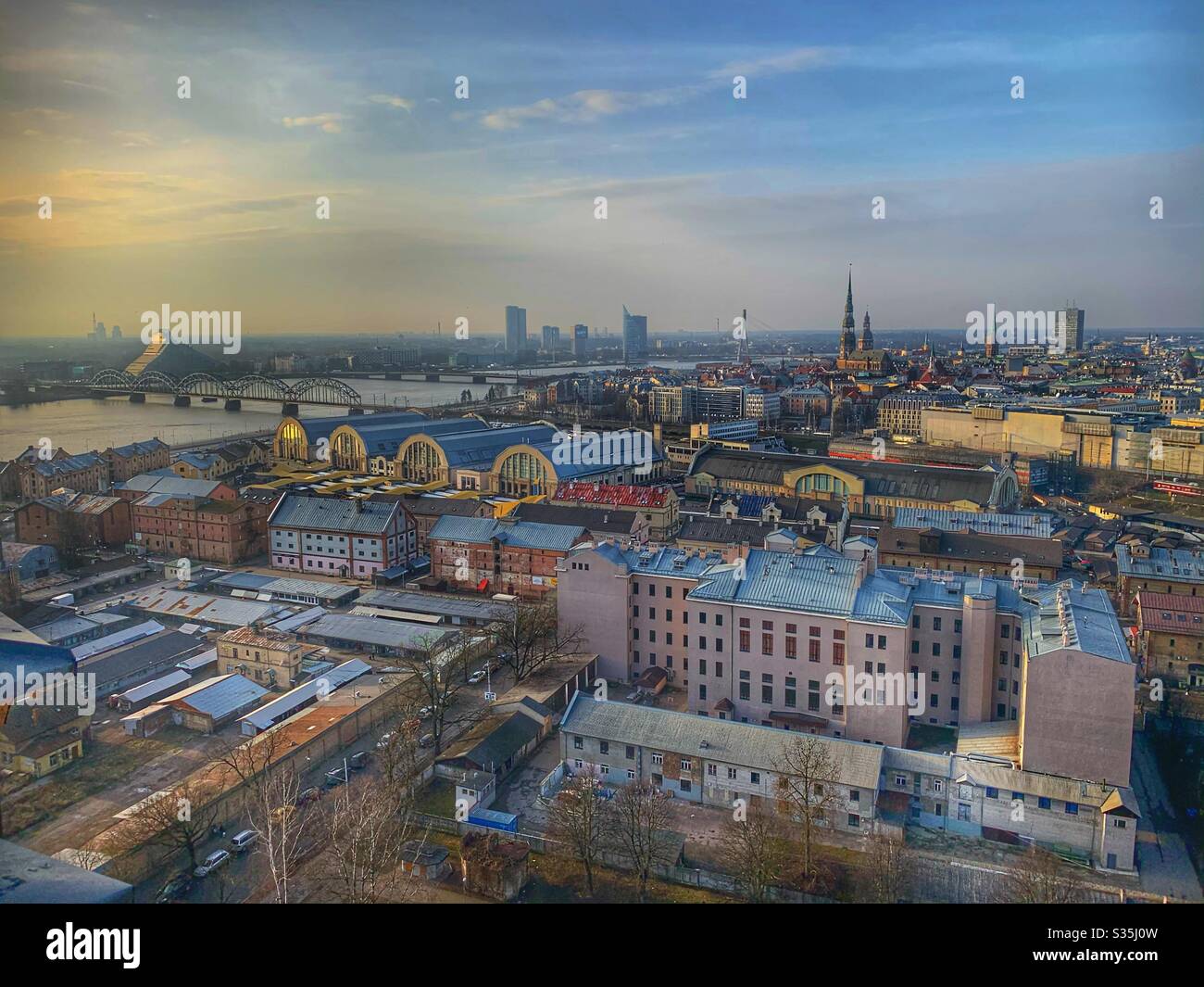Ein Blick auf Riga, Lettland am Ende des Tages kurz vor Sonnenuntergang. Im goldenen Licht gebadet und Blick auf die Stadt und den Fluss aus einer Höhe. - Smartphone-aufgenommenes Stockfoto