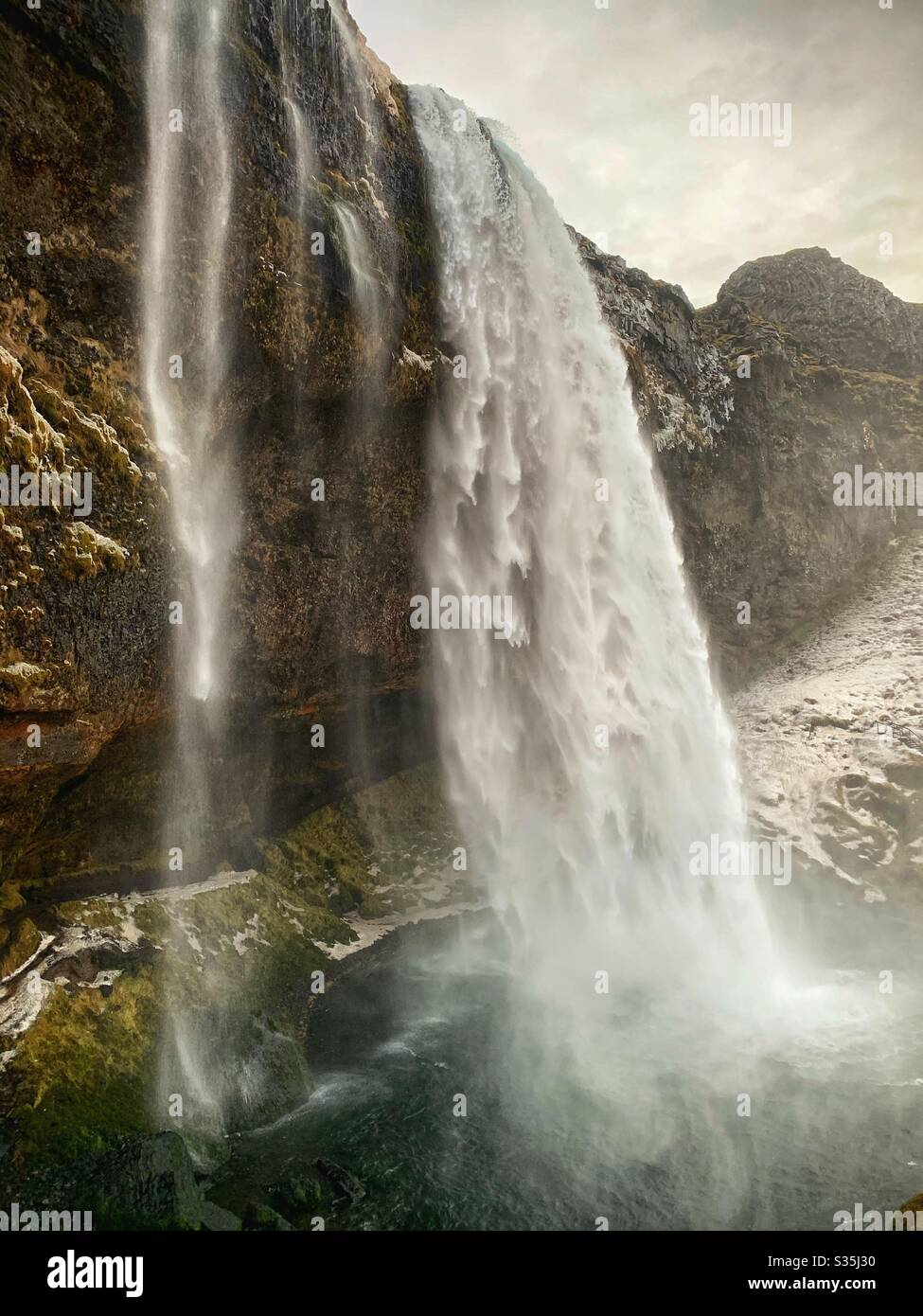 Kolossaler Wasserfall in Island. Verschneiten Boden. Schiere Felswand. Seljalandsfoss, Island. Stockfoto