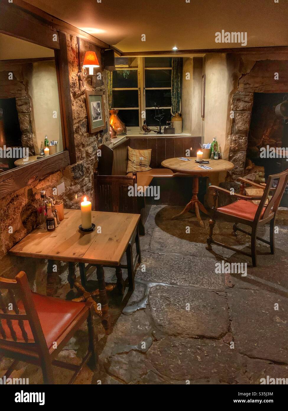 Altmodischer englischer Pub, das Gebäude stammt aus dem 16. Jahrhundert. Rustikale Einrichtung, Steinfußboden, stimmungsvolle Beleuchtung und Kerzen. Stockfoto