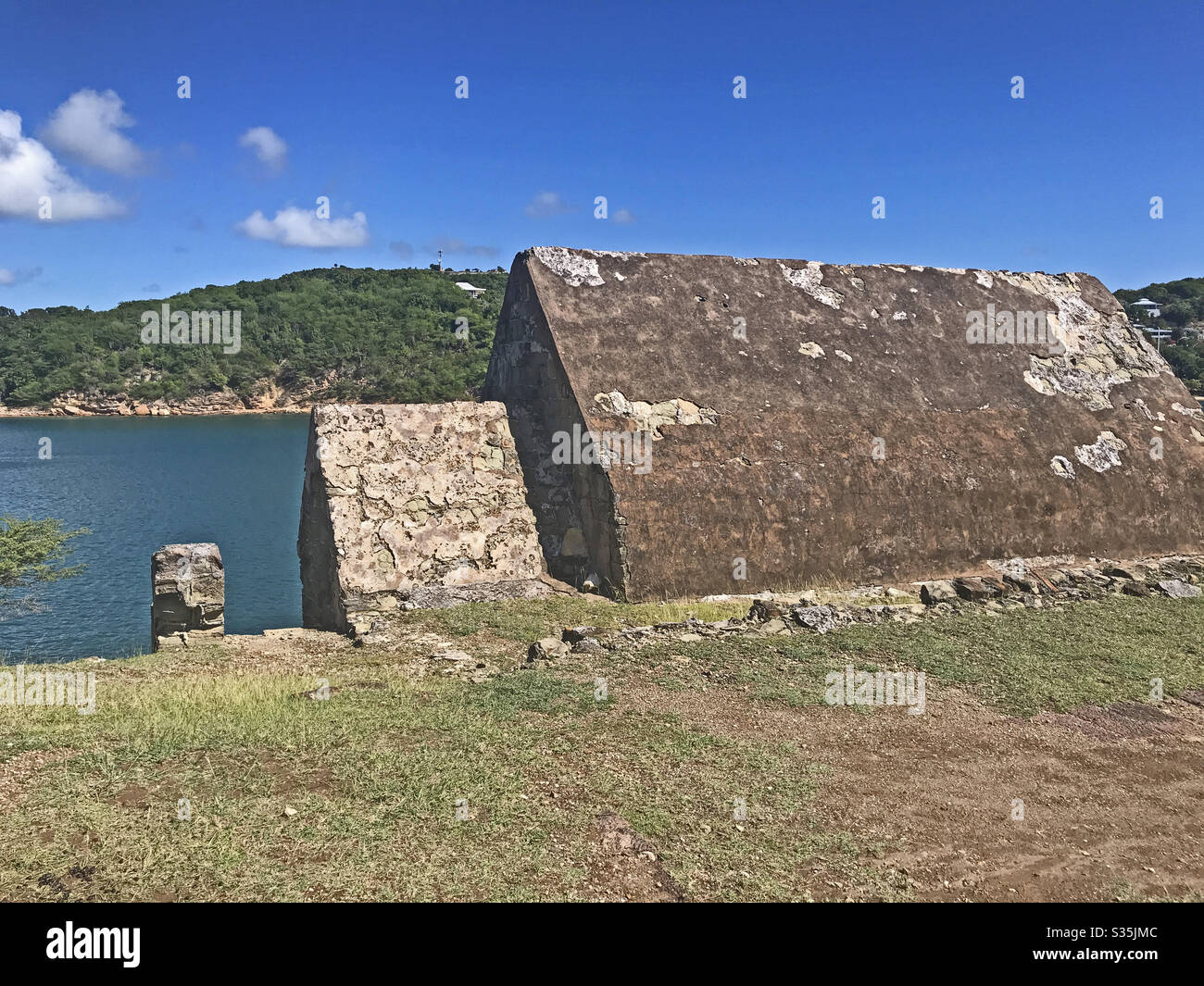 Powder Magazine in Fort Berkeley in Antigua und Barbuda, Karibik, Kleinantillen, Westindien mit englischem Hafen im Hintergrund und blauem Himmel Kopierraum. - Smartphone-aufgenommenes Stockfoto