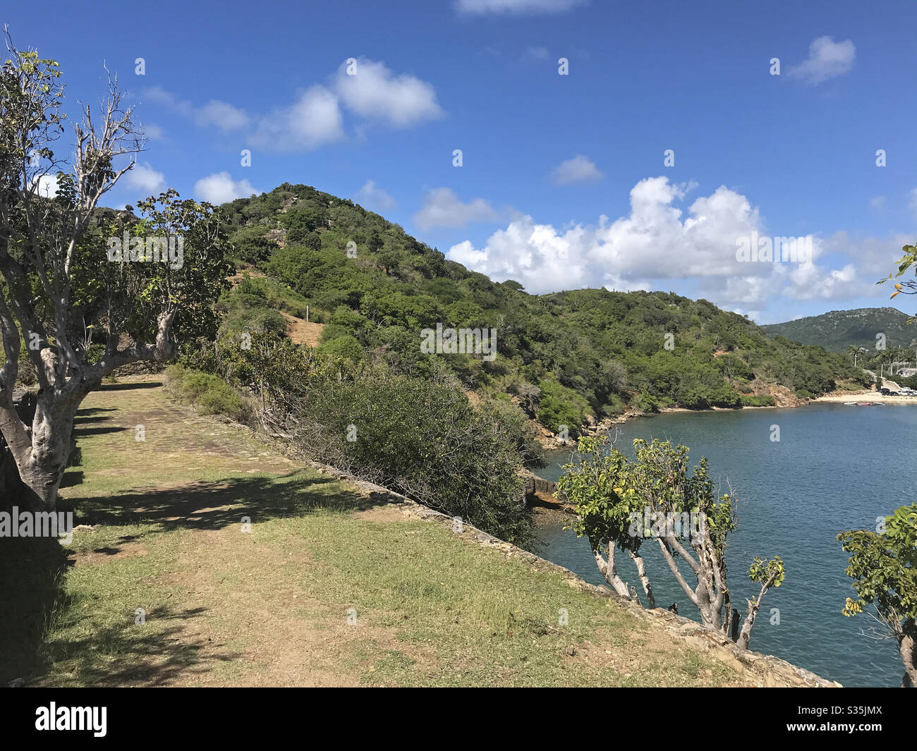 Pfad führt in und aus Fort Berkeley durch den englischen Hafen in Antigua und Barbuda, Karibik, kleine Antillen, Westindien mit blauem Himmel Kopierraum. - Smartphone-aufgenommenes Stockfoto