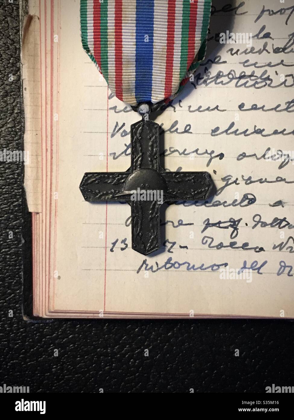 Alte italienische Gedenkmedaille für Kriegsehrungen auf einer Seite von Notizbuch handgeschrieben Stockfoto