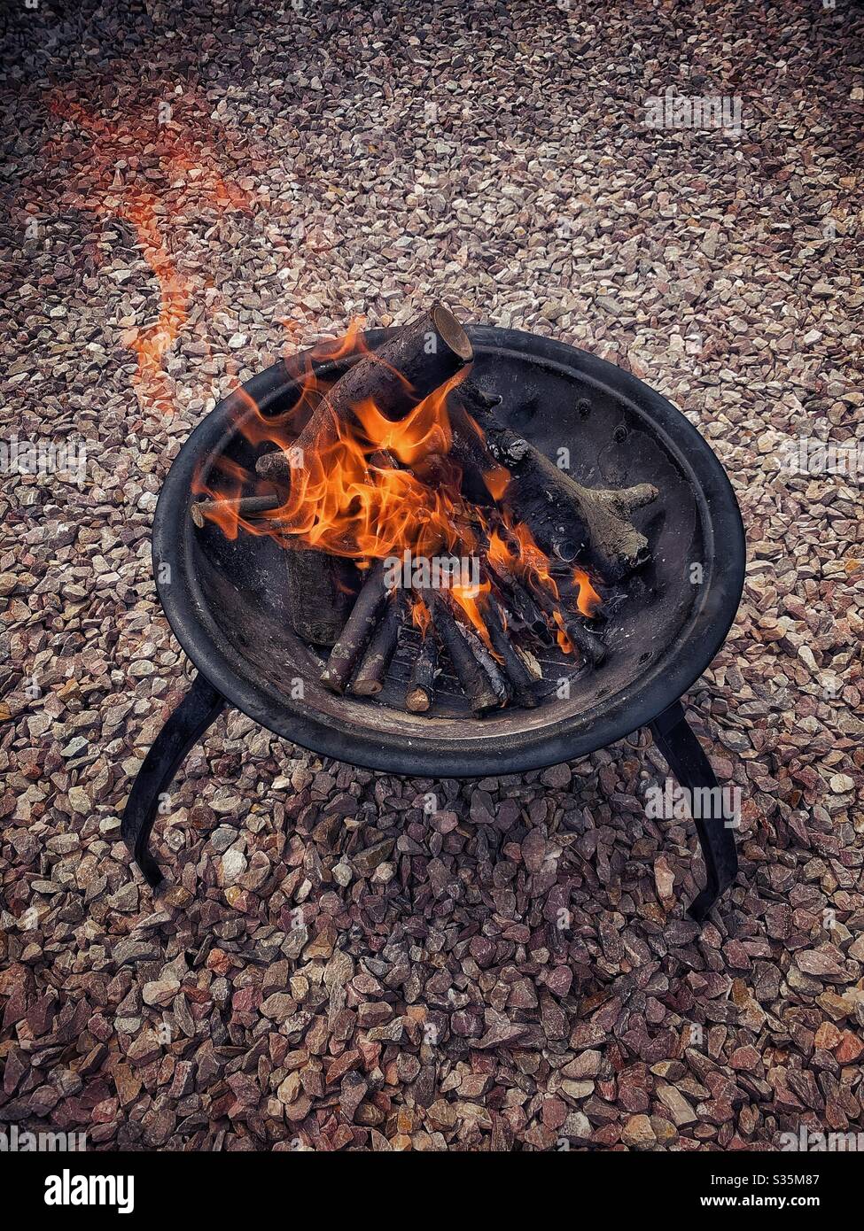 Großes Feuer in einer Feuerstelle, auf Kies. Stockfoto