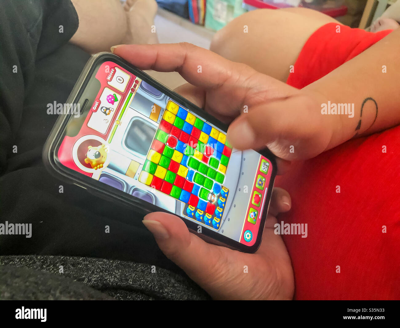 Eine Frau spielt ein Spiel auf ihrem Handy. - Smartphone-aufgenommenes Stockfoto
