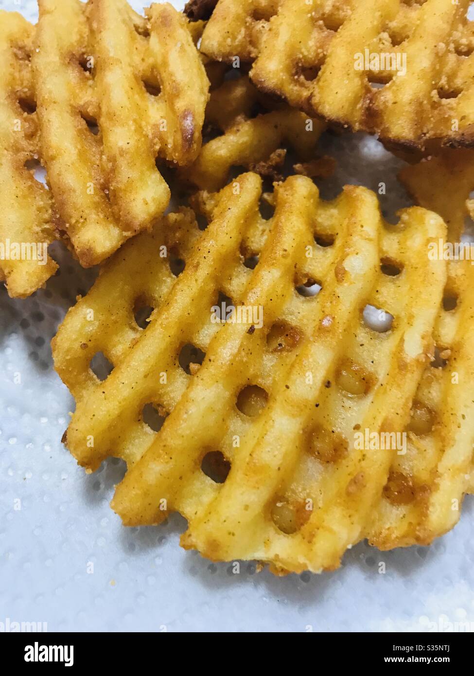 Hausgemachte frittierte Kartoffelwaffel frittiert Pommes in einem Seidenpapier, um Öl abzulassen - schneller Snack, Kindermahlzeit, Pommes Frites, Fenster wie Pommes Stockfoto