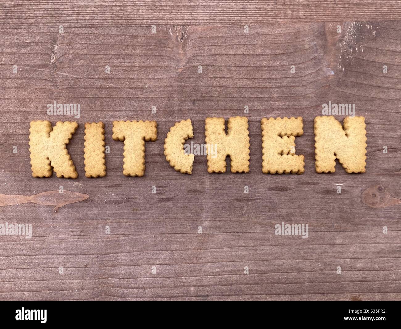 Küche Wort mit Keksbuchstaben über einem Holzbrett komponiert - Smartphone-aufgenommenes Stockfoto