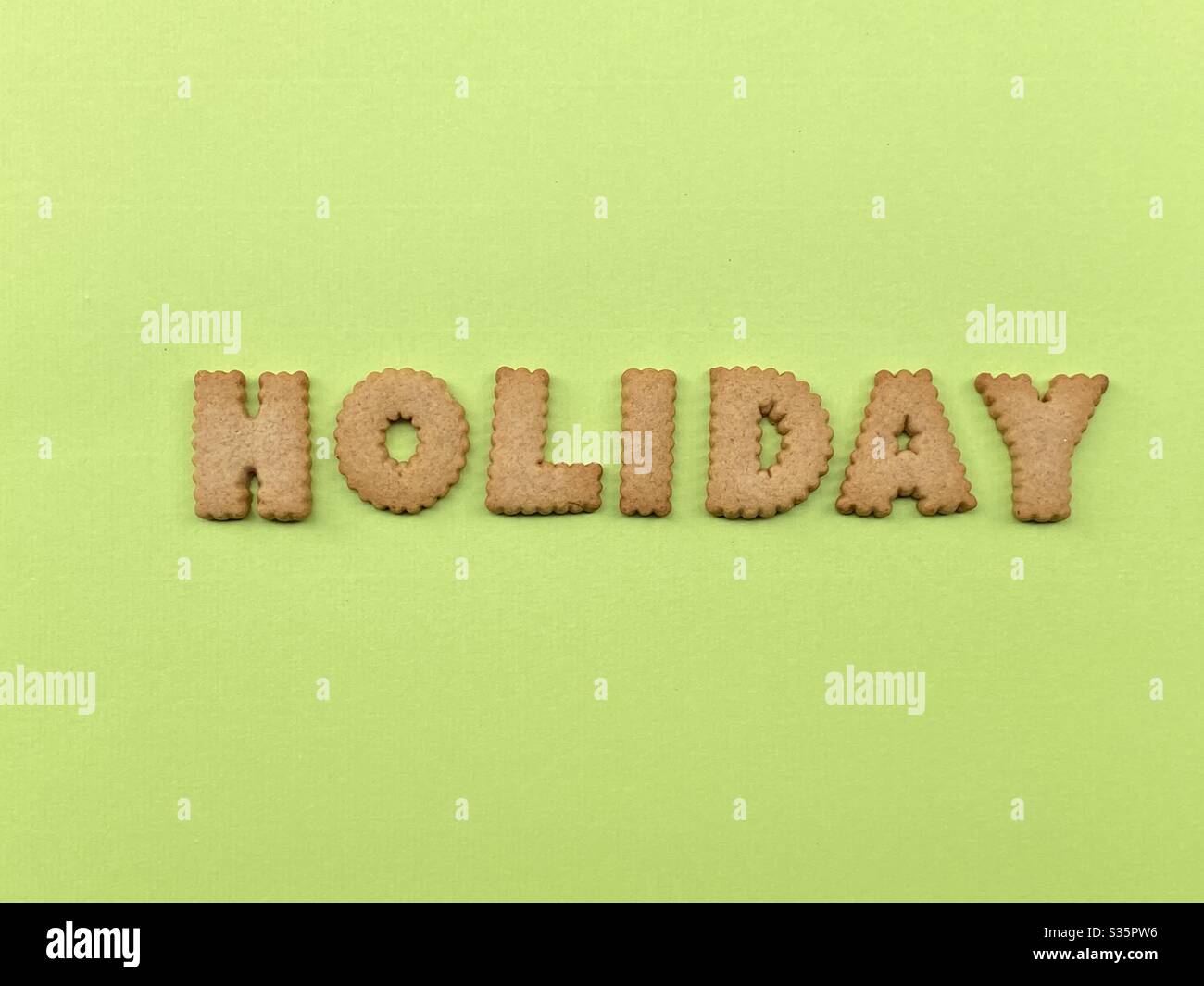 Urlaubswort mit Cookie-Buchstaben über grün - Smartphone-aufgenommenes Stockfoto