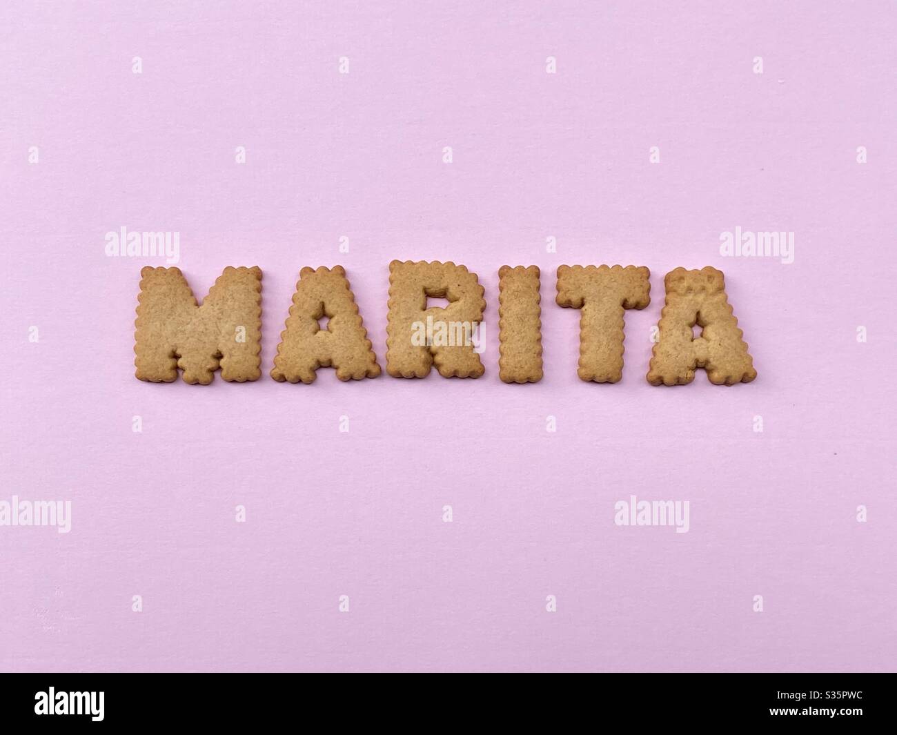 Marita, weiblicher Vorname, bestehend aus Keksbuchstaben über rosa Farbe - Smartphone-aufgenommenes Stockfoto